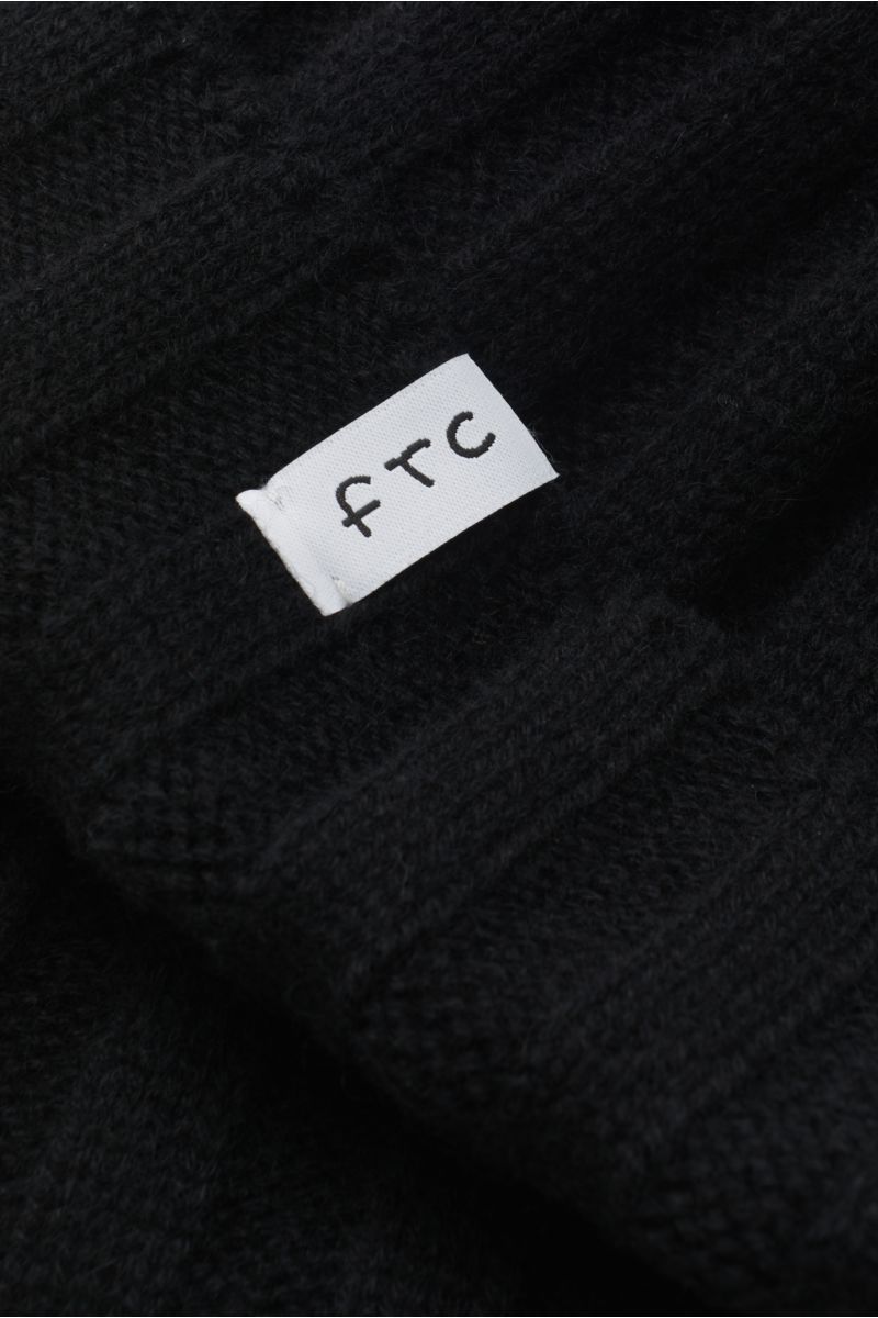 Nahaufnahme der FTC Cashmere Mütze schwarz aus feinstem Fair-Trade-Cashmere mit Rippstrickmuster und schmalem Umschlag.