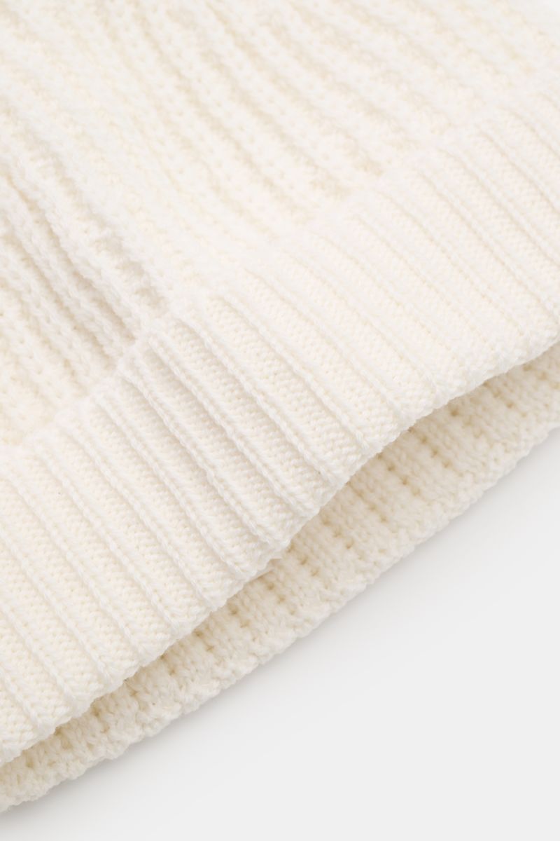 04651/ A trip in a bag Wollmütze 'Foggy Hat' creme, nah aus schräger Perspektive, reine Wolle, weicher Griff, garment dyed, Rippstrick, schmaler Umschlag.