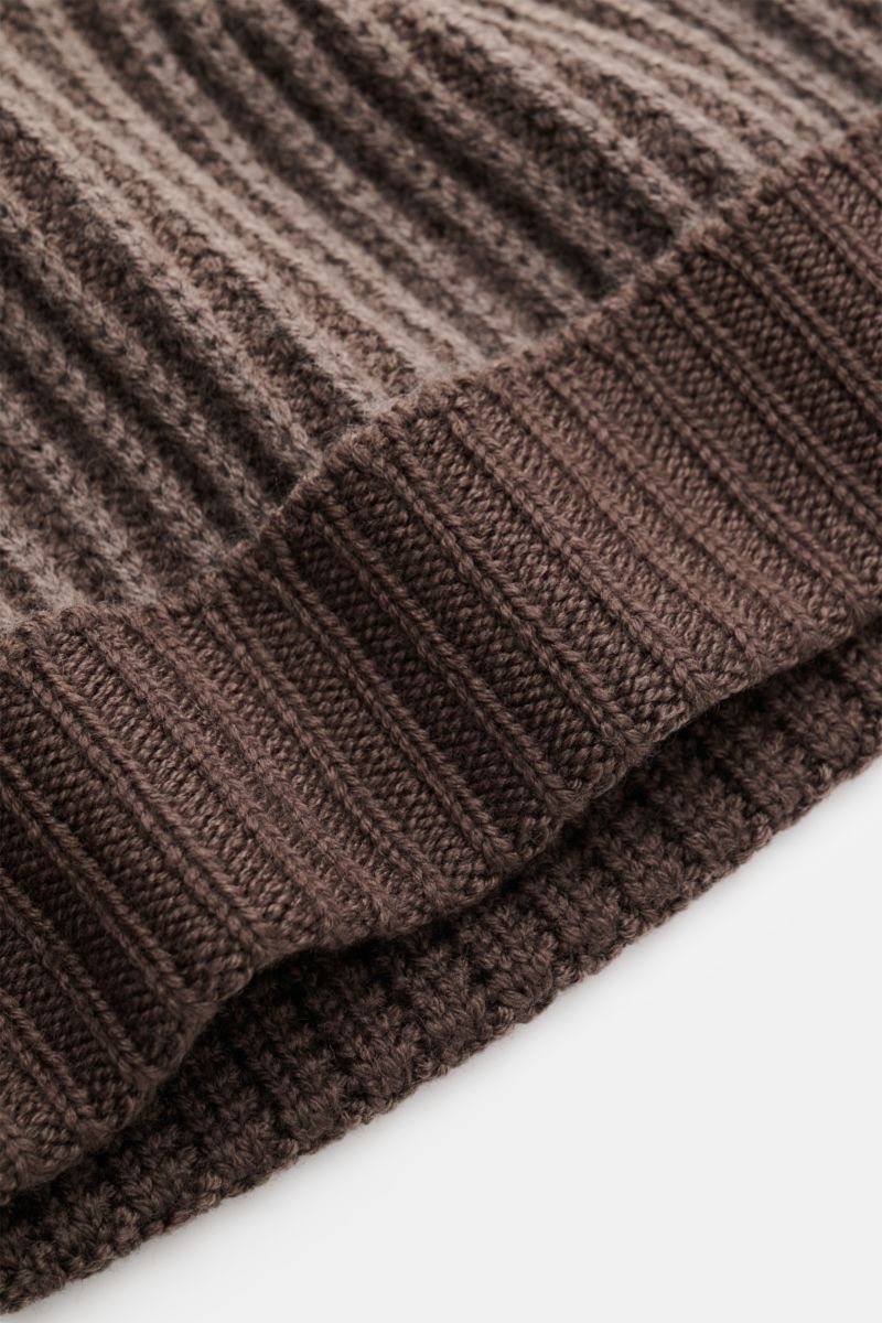 Nahaufnahme aus schräger Perspektive der 04651/ A trip in a bag Wollmütze 'Foggy Hat' graubraun mit markantem Rippstrickmuster, schmalem Umschlag, weichem Griff aus reiner, garment dyed Wolle.