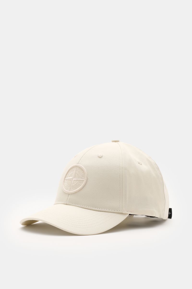 Stone Island Baseball-Cap creme shown from a front-left angle, made of pure cotton with tonal compass stitching and curved brim.
