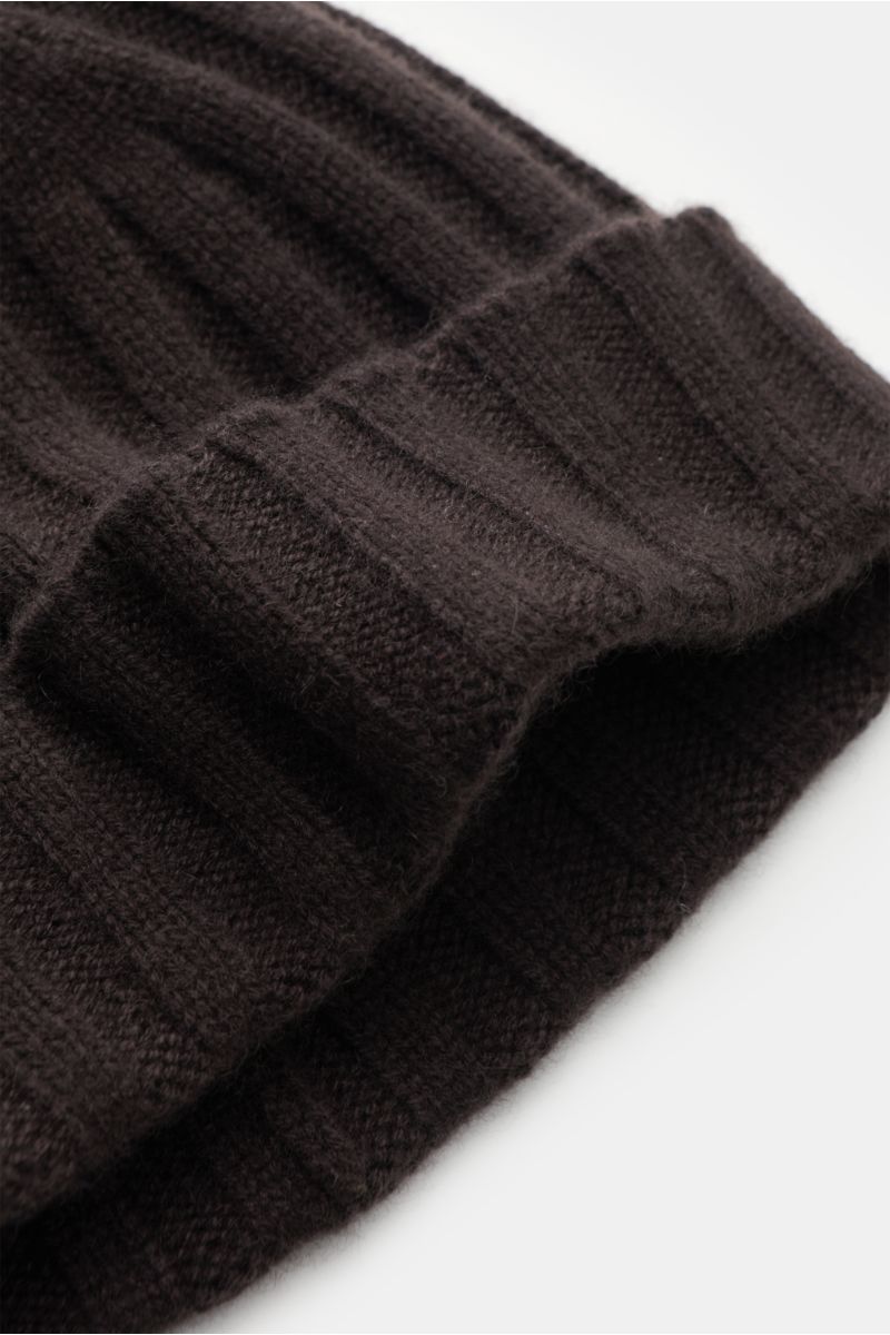 Nahaufnahme der von Braun Cashmere Mütze dunkelbraun aus reinem mongolischem Cashmere mit feinem, weichem Rippstrickmuster und schmalem Umschlag, liegend fotografiert.