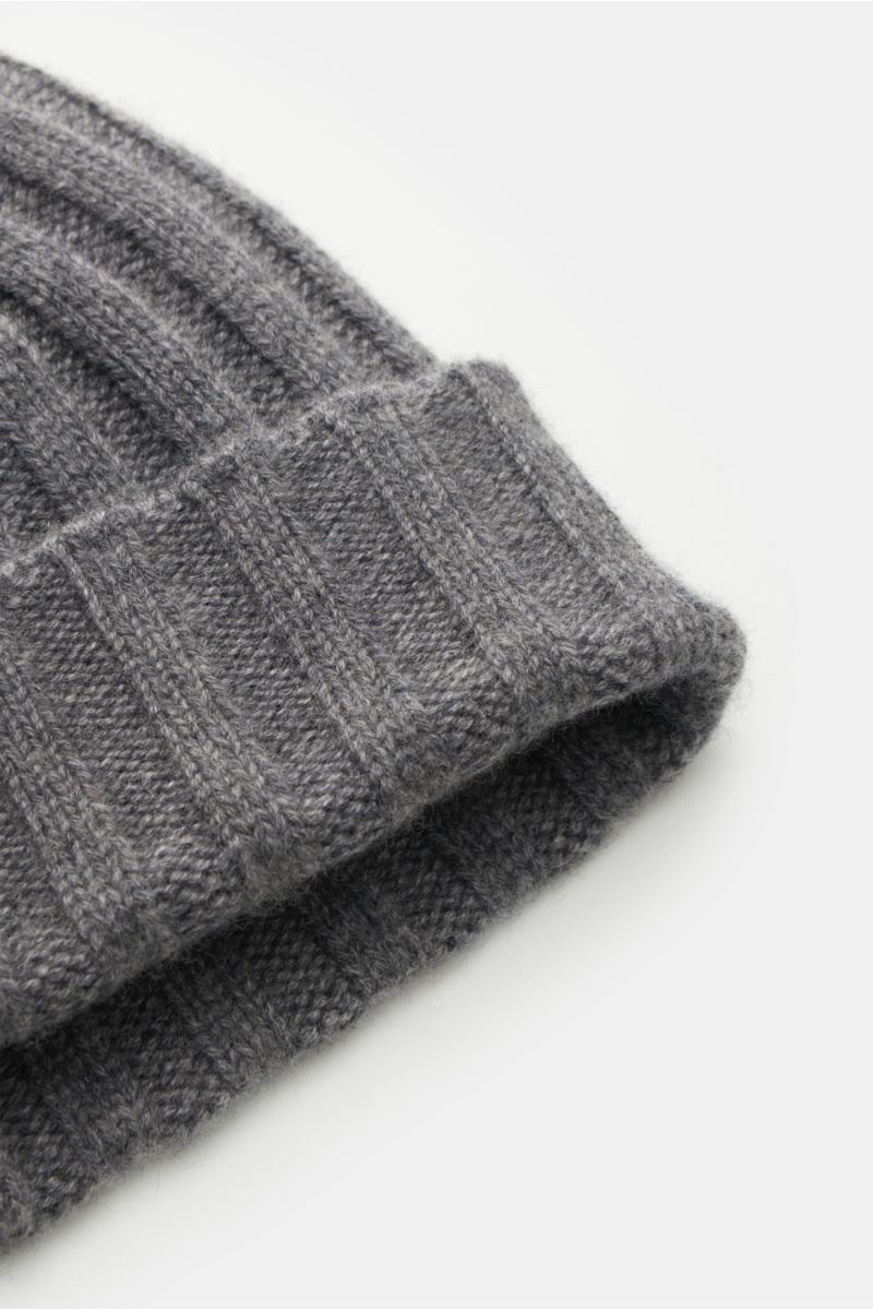 Close-up, angled view of the von Braun Cashmere beanie grey mottled showcasing its fine rib knit pattern and small turn-up cuff. Whether worn with a classic winter coat or a highly functional down jacket, this soft VON BRAUN knitted beanie made of pure Mo