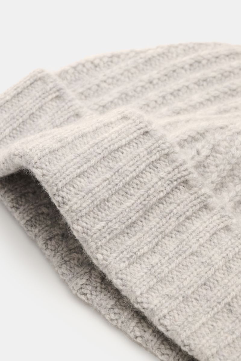 Close-up side view of the 04651/ A trip in a bag Cashmere Mütze hellgrau meliert, a luxurious light grey marled cashmere hat with wide cuff in a soft ribbed knit pattern.

Luxuriöses Winter-Accessoire: Die edle Cashmere-Mütze aus der ‚Look o