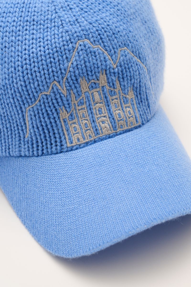 Close-up front-side view of the 04651/ A trip in a bag Cashmere Baseball-Cap blau in soft blue, featuring fine knit visor and stitched Milan Cathedral and Cortina mountain peaks.

Luxuriöses Winter-Highlight: Die Baseball-Cap aus der 'Look o
