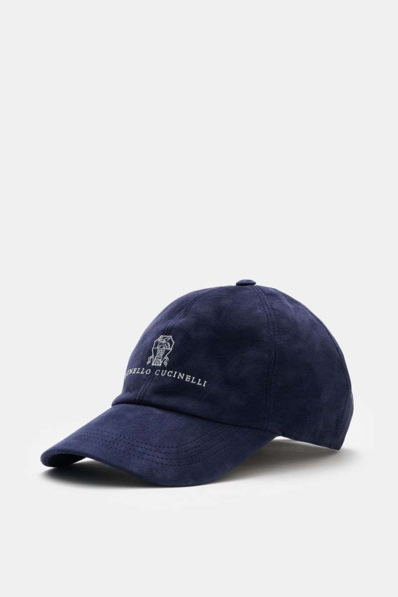 Brunello Cucinelli Veloursleder-Cap dunkelblau shown from a front-side angle, made of soft velour leather with logo stitching, six-panel style, curved brim, adjustable leather strap, and cotton lining, a sportive accessory in noble quality, made in Italy.