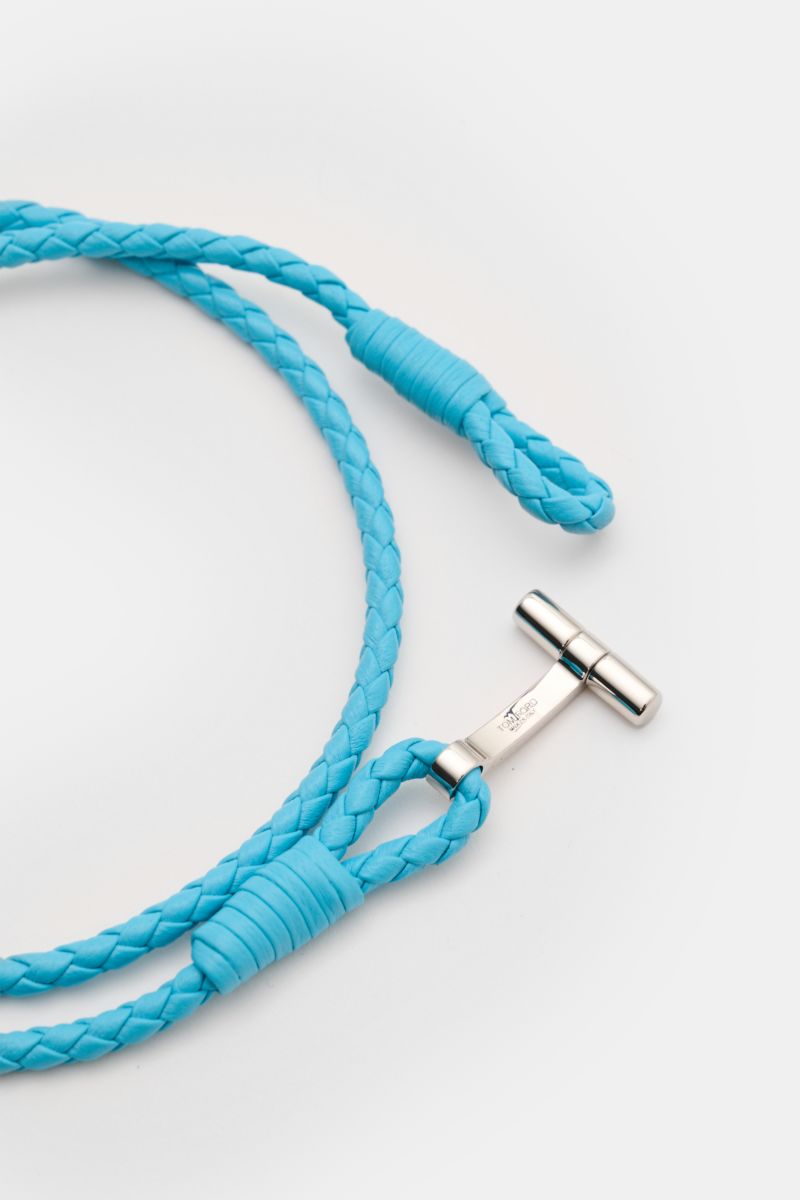 Close-up top view of Tom Ford Armband azurblau/silber with braided smooth azure blue leather and gold-colored T clasp, delicate branding.

Wählen Sie mit dem schmalen Lederarmband aus geflochtenem Leder und mit goldfarbenem T-Verschluss von Luxus-Desig