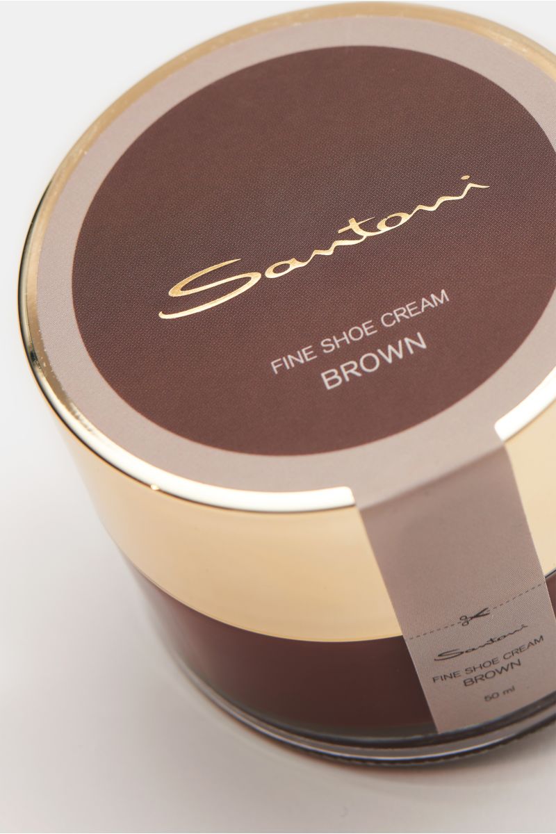 Close-up, top-down angled view of Santoni Schuhcreme braun 50 ml, a brown shoe cream tin with gold lid, essential for hand-crafted Santoni shoes, featuring high wax content, smooth leather care, color and shine refresh, made in Italy.