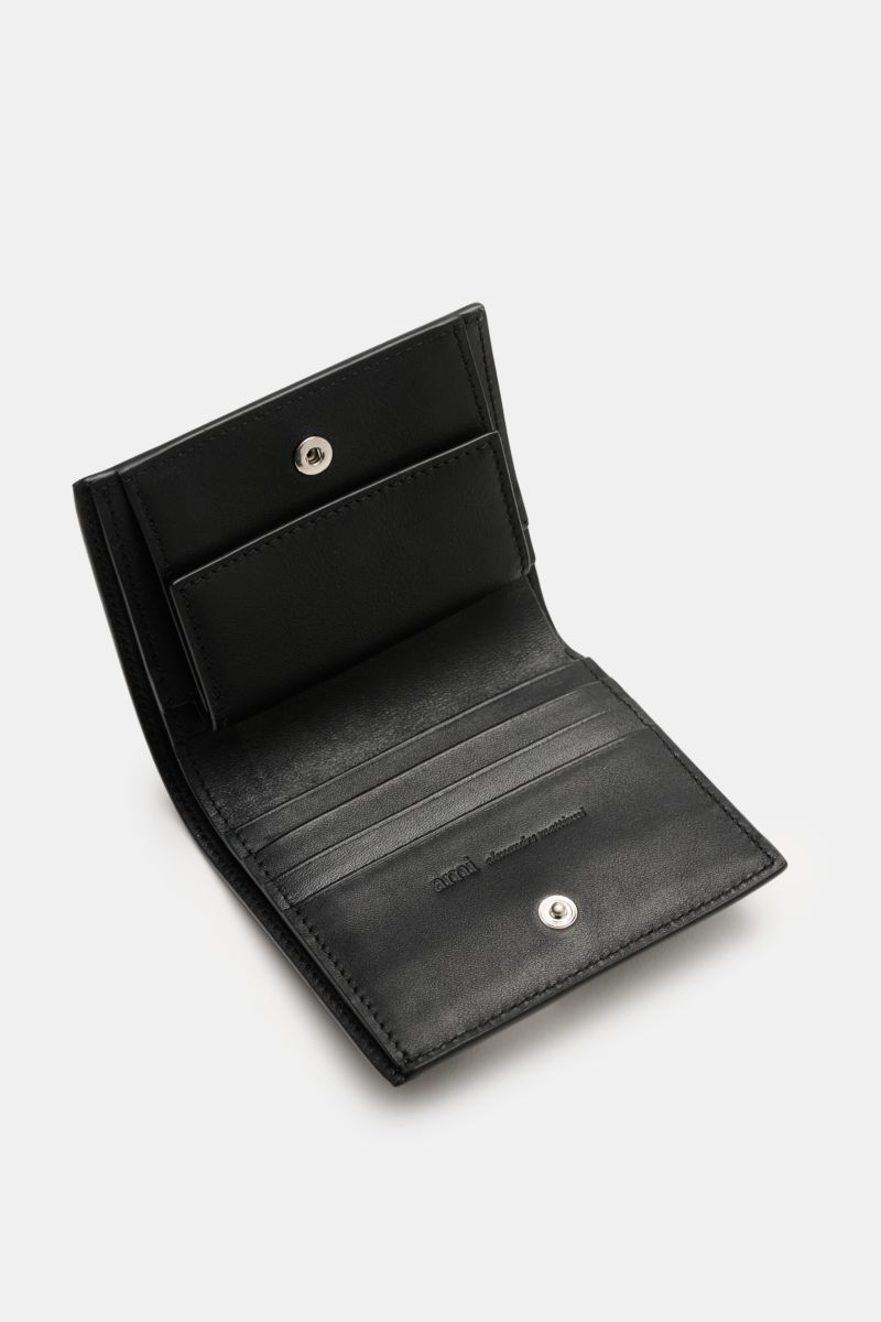 Open Ami Paris Portemonnaie schwarz wallet made of finely grained black calf leather, shown from a top angled view, with one banknote compartment, four card slots, a coin pocket with a snap button, front logo, and closed size approx. 11 cm x 9 cm; Stil