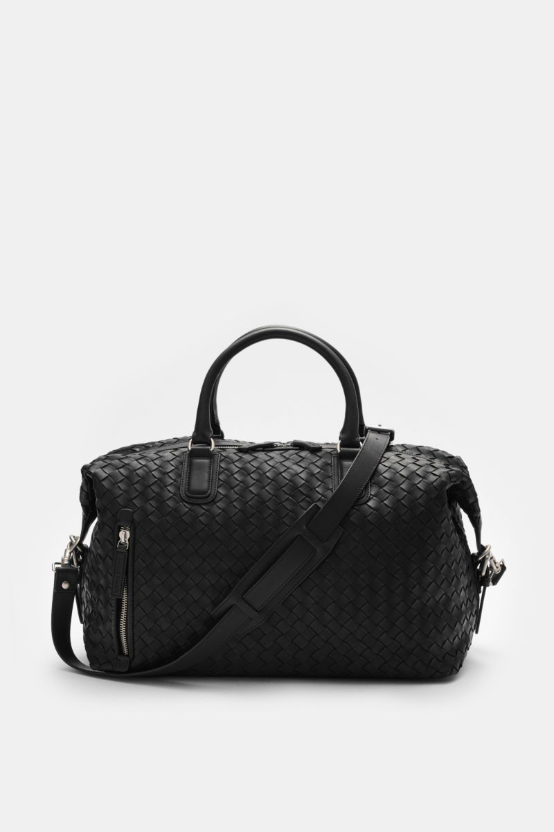 Front view of the Officine Creative Weekender schwarz, a spacious, handwoven black leather bag with matte silver hardware, robust handles, adjustable shoulder strap, and zippered compartments, perfect for short trips. Mit diesem geräumigen, variabel tr