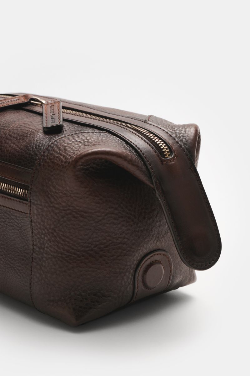 Close-up side view of Officine Creative Necessaire dunkelbraun in dark brown finely grained calf leather with silver hardware and zipper details.

