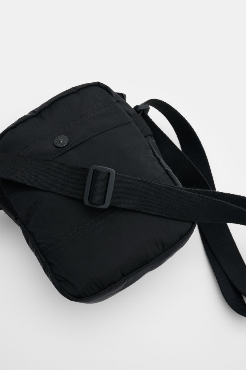 Stone Island Crossbody Bag 'Marsupio Tracolla' schwarz shown from a top-down angle, featuring black microfiber material, adjustable strap, multiple pockets, and signature patch. Praktisch und stylish zugleich: Die Crossbody Bag 'Marsupio Tracolla' von STO