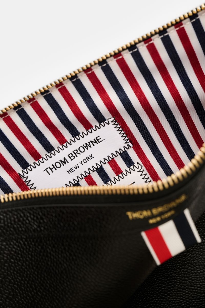 Close-up inside view of the Thom Browne Dokumentenmappe schwarz showing striped interior fabric with a stitched brand label and gold zipper from above.

Die Dokumentenmappe aus edlem Leder von THOM BROWNE wird mit dem markentypischen Grosgrain zum Eyec