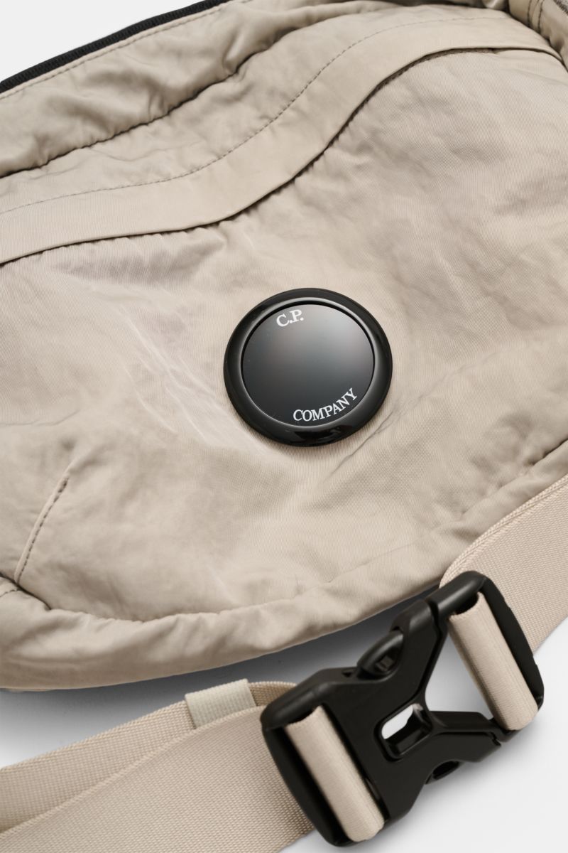 Close-up, top-down view of C.P. Company Belt bag grey showing water repellent microfibre fabric, signature lens, and adjustable strap buckle.