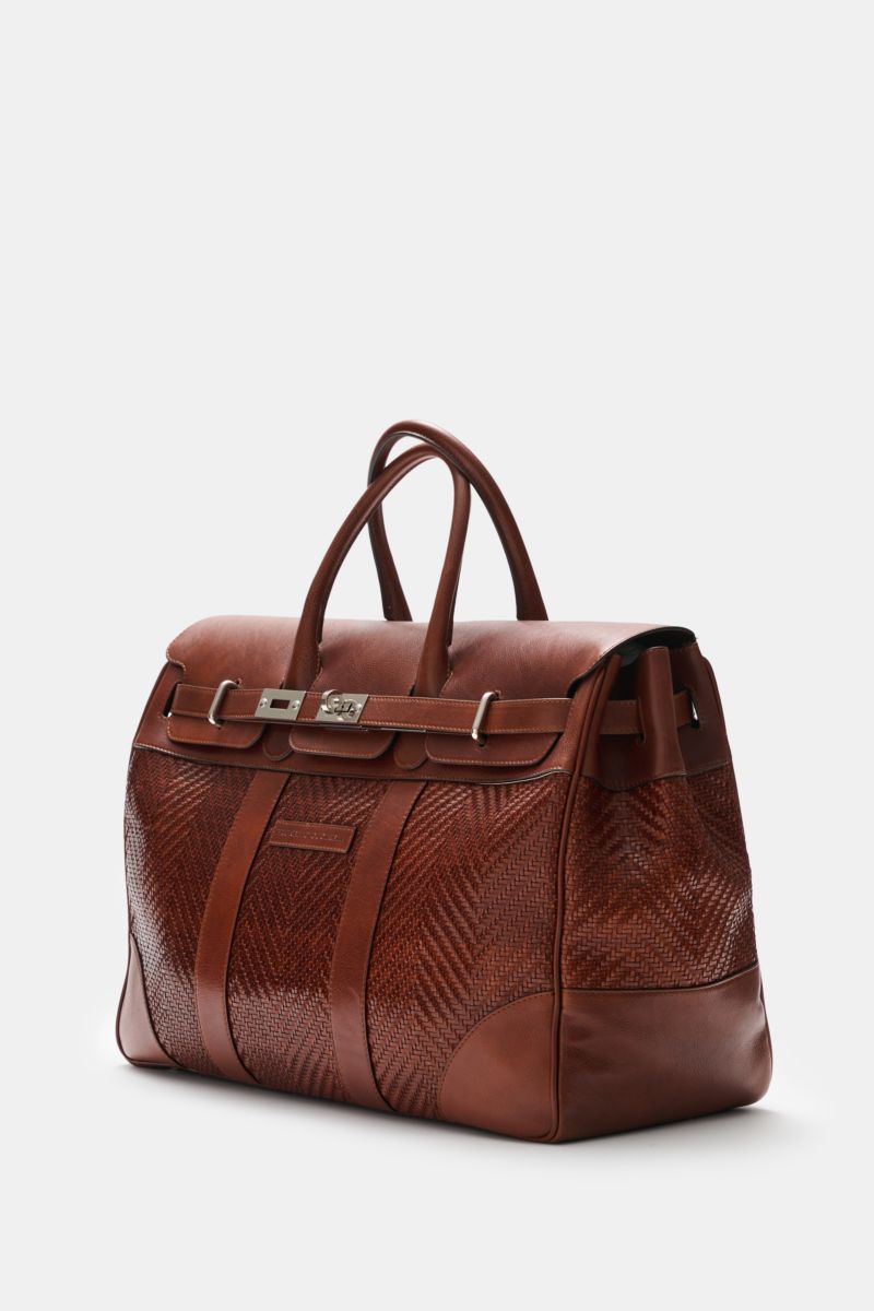 Brunello Cucinelli Weekender bordeaux shown from a front-side angle, in genarbtes calf leather with gold hardware, robust handles, adjustable leather buckle, spacious main and zippered interior compartments, water-repellent textile lining, leather address