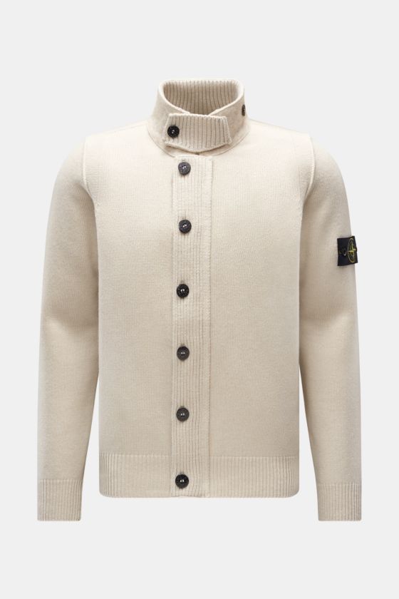 Stone Island Strickjacke 'Lambswool' sand, frontale Ansicht mit Stehkragen, Knopfleiste, Filz-Details, Linksstrick und Kompass-Badge am Ärmel. Stone Island Strickjacke 'Lambswool' sand, frontale Ansicht mit Stehkragen, Knopfleiste, Filz-Details, Linksstrick und Kompass-Badge am Ärmel.