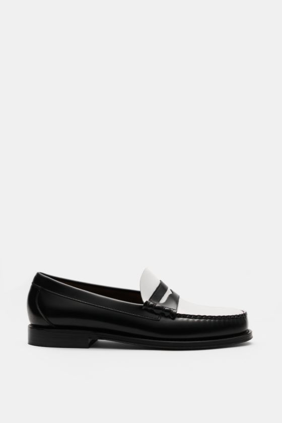 G. H. Bass Penny Loafer schwarz/weiß aus edlem Glattleder, seitliche Seitenansicht mit schmal zulaufender Silhouette, Penny Strap, Zierschnürung, Lederfutter, komfortables Fußbett, Ledersohle mit kautschukverstärktem Absatz. G. H. Bass Penny Loafer schwarz/weiß aus edlem Glattleder, seitliche Seitenansicht mit schmal zulaufender Silhouette, Penny Strap, Zierschnürung, Lederfutter, komfortables Fußbett, Ledersohle mit kautschukverstärktem Absatz.