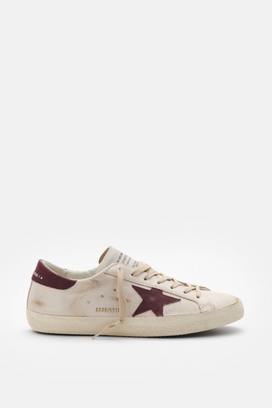 Golden Goose Sneaker 'Super-Star Classic' offwhite/bordeaux seitlich fotografiert mit Vintage-Finish, handgemachtem Used-Look, Nappaleder, Stern und Gummisohle. Golden Goose Sneaker 'Super-Star Classic' offwhite/bordeaux seitlich fotografiert mit Vintage-Finish, handgemachtem Used-Look, Nappaleder, Stern und Gummisohle.