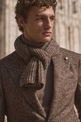 Close-up side view of a male model wearing a dark light brown and dark brown checkered blazer from Luigi Bianchi, paired with a taupe melange cashmere turtleneck sweater from B.F. Knitwear, and a taupe and dark brown melange scarf from Agnona wrapped styl