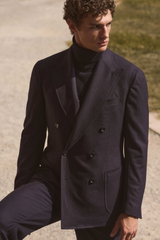 Front angled view of a male model wearing a navy melange double-breasted suit named 'Andrea' from Stile Latino with a navy cashmere turtleneck sweater from Aida Barni, featuring refined tailoring and luxurious textures in a deep navy color palette, captur
