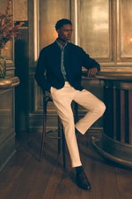 Shop by Look 13 Edition Vol. 19 shows a model seated in a side view, wearing a blue chambray shirt with shark collar by Finamore, white "The Rebel" pants from PT Torino, a dark brown Veneta Cinture belt, and dark brown "Moro" penny loafers by Henderson, b