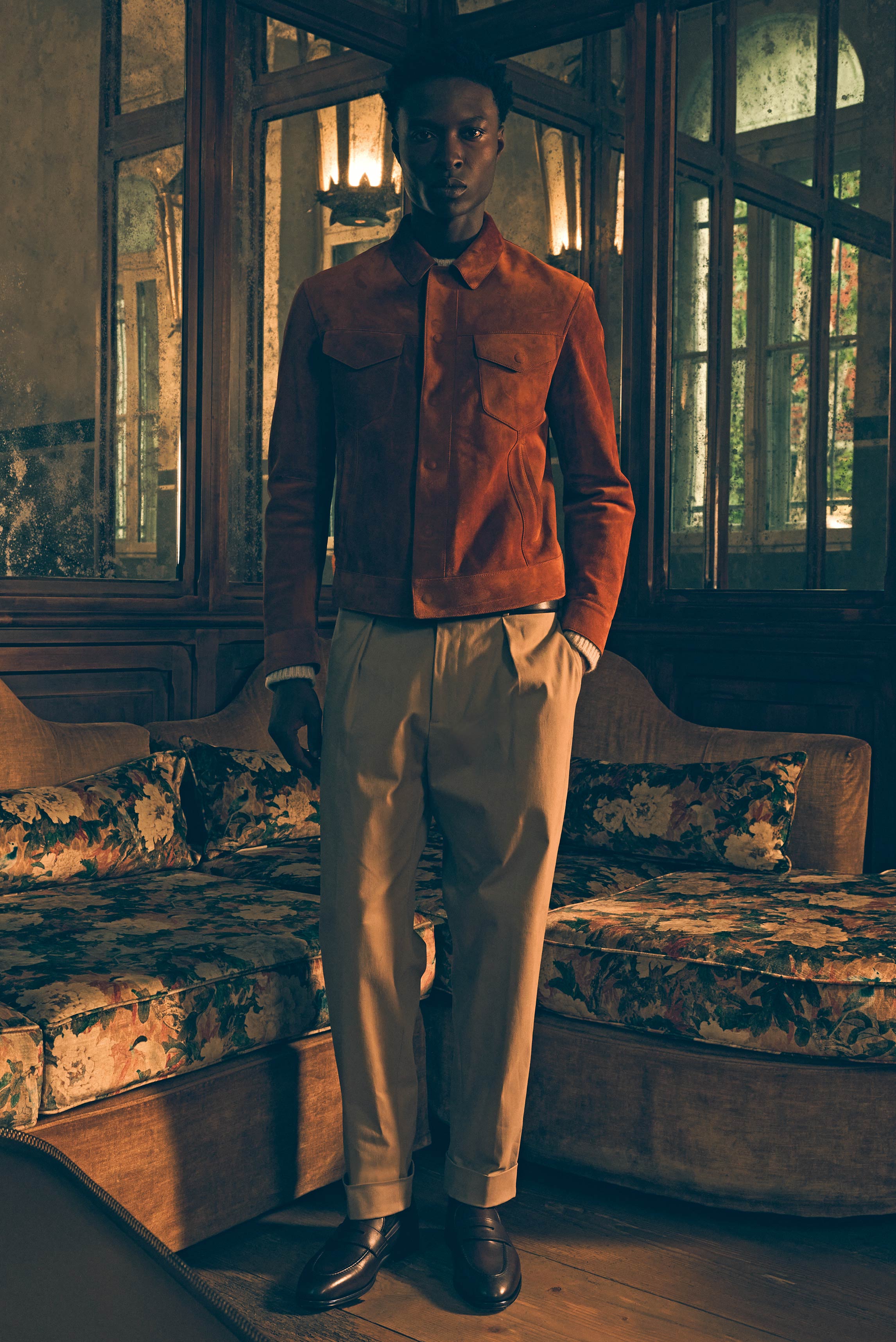 Frontalaufnahme eines Modells im Raum mit antikem Sofa, trägt braune Velourslederjacke Tom Ford, sandfarbenen Cashmere-Seide Pullover Iris von Arnim, taupefarbene Chino Berwich, dunkelbrauner Gürtel Veneta Cinture, Penny Loafer Henderson – Shop by Look 14