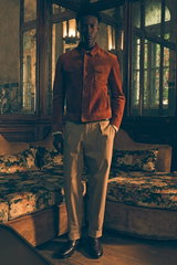 Front view of a model in a vintage room wearing a brown suede jacket from Tom Ford, sand cashmere-silk sweater Felton by Iris von Arnim, taupe chinos Chiaia from Berwich, dark brown penny loafers Moro by Henderson, and matching belt from Veneta Cinture. T