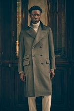 Front view of a model in Shop by Look 16 Edition Vol. 19 wearing a sophisticated grey-green melange double-breasted Brunello Cucinelli coat with large buttons and pockets, a light grey melange and taupe patterned turtleneck sweater, and sand-colored cordu