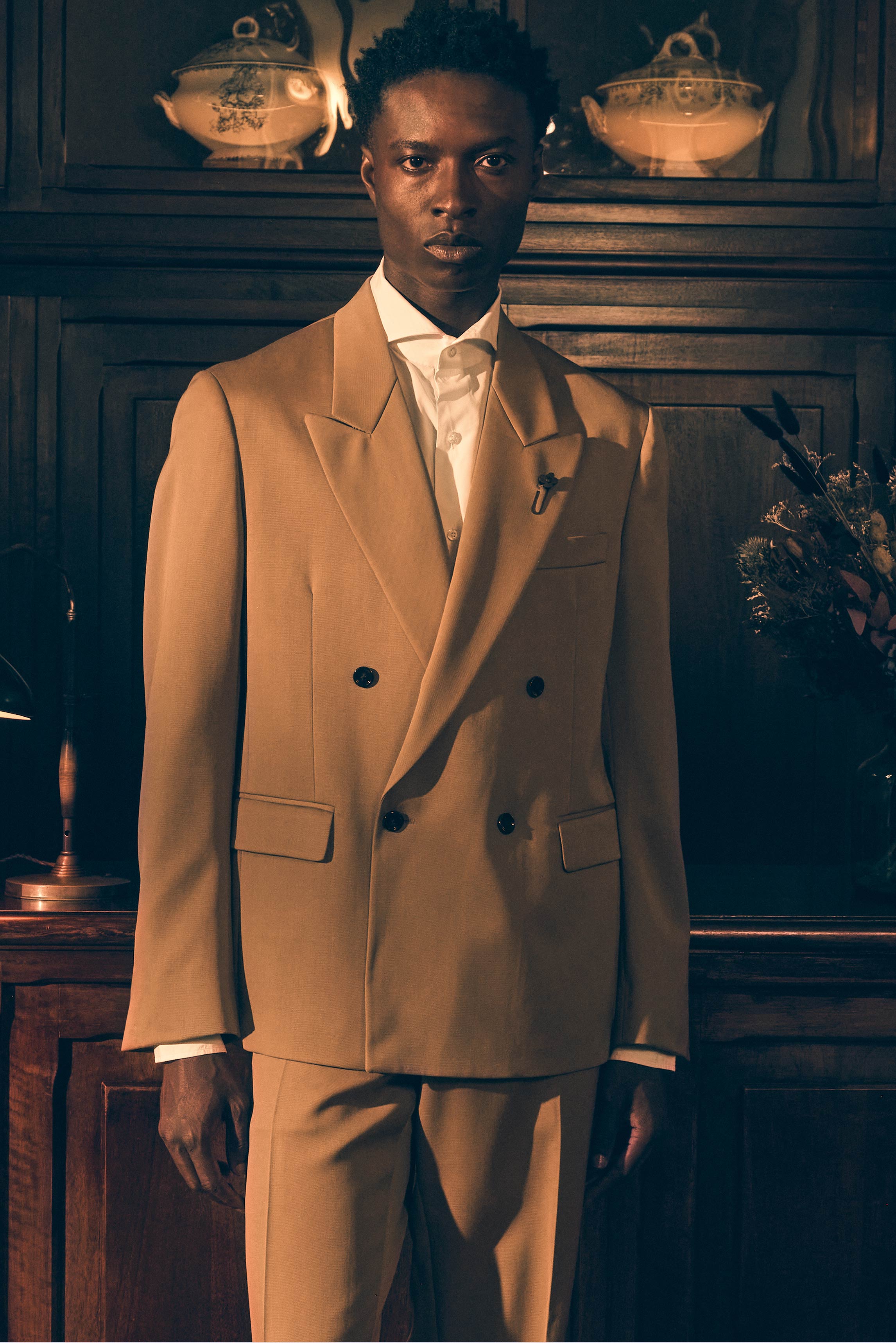 Junger Mann frontal fotografiert im eleganten Shop by Look 23 Edition Vol. 19 mit hellbraunem Lardini Sakko, weißem Borrelli Hemd 'Luciano' und passender Lardini Hose.