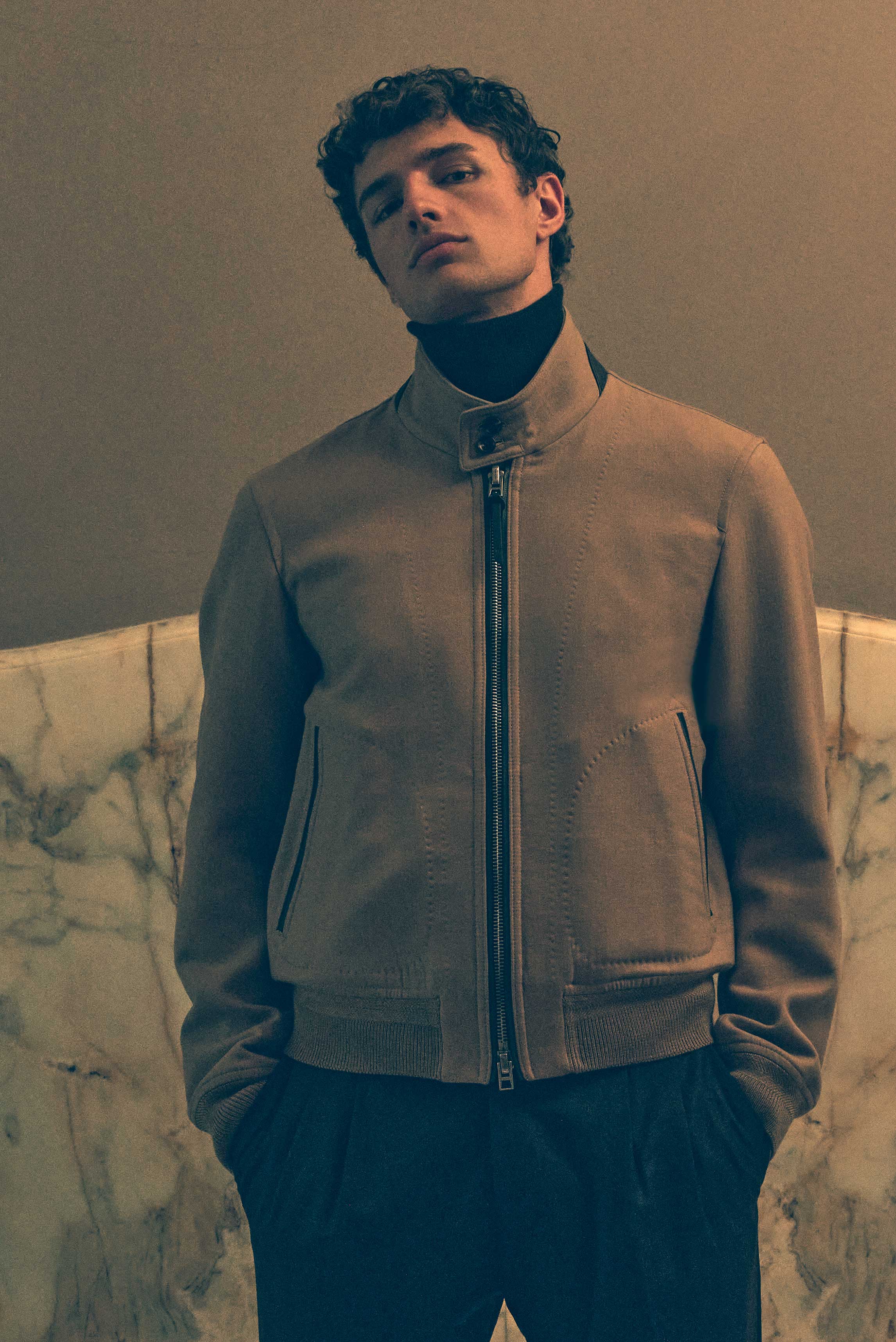 Porträt von vorne zeigt das Model im hellbraunen Tom Ford Blouson mit Reißverschluss, dunkelbraunem Malo Kaschmir-Rollkragenpullover und Incotex Wollhose in Shop by Look 40 Edition Vol. 19, edel in Brauntönen.