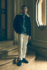 Front view of a male model standing on marble stairs in an elegant interior, wearing the navy "Double Blouson" jacket with cream shearling collar, smoky blue ribbed mock neck pullover, and cream corduroy pants, styled in Shop by Look 43 Edition Vol. 19, s