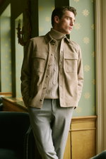 Shop by Look 09 HW 2026 shows a side-front view of a model wearing a beige suede Agnona overshirt with button-down front and flap pockets, a light beige cable-knit turtleneck sweater underneath, and light gray trousers, creating a sophisticated, elegant o