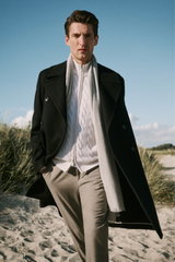 Männliches Modell frontal fotografiert, trägt schwarzen Mantel von Barena Venezia, weißen grob gestrickten Pullover, graue Hose von Closed – Shop by Look 41 HW 2026.