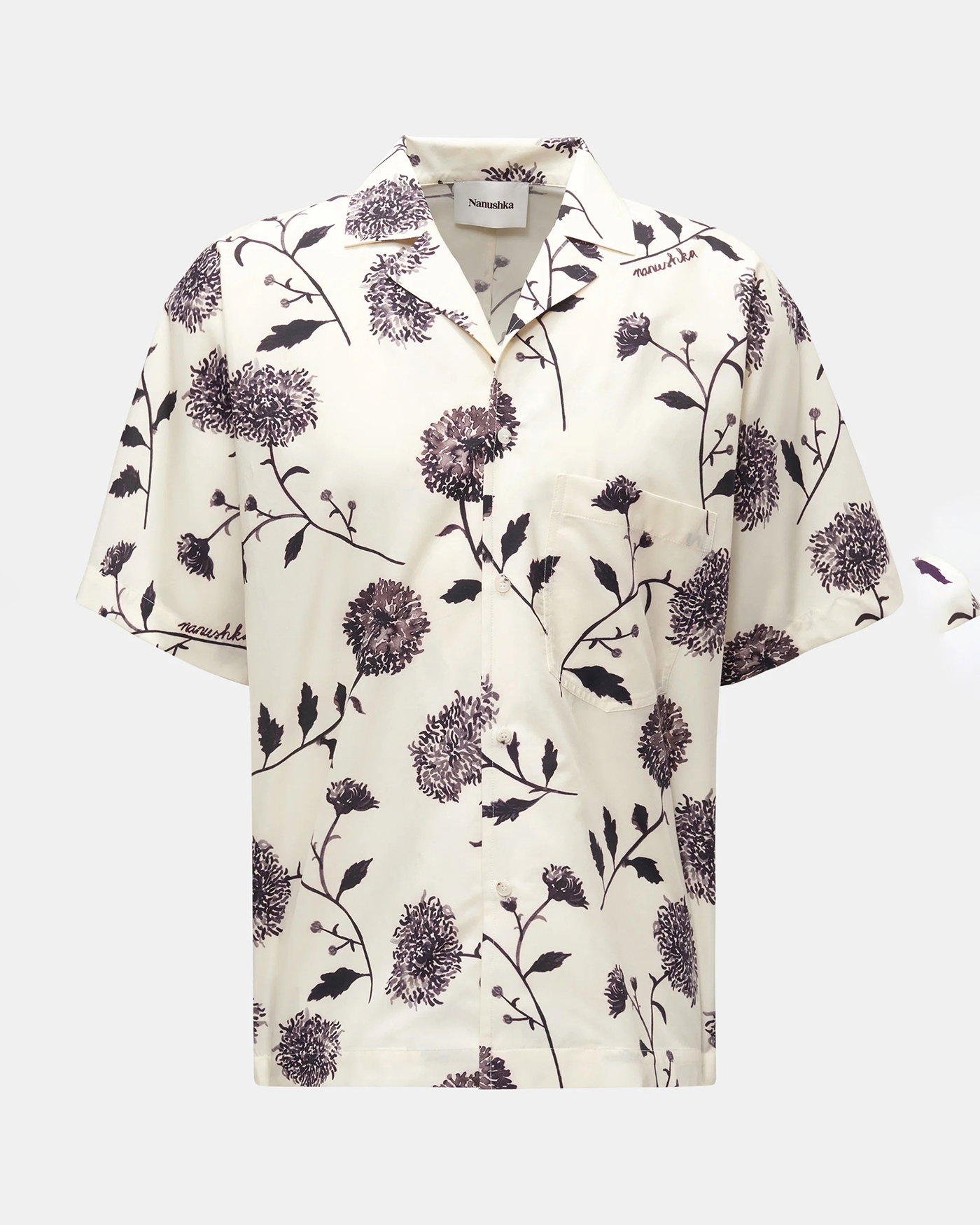 Herren-Kurzarmhemd in Creme mit dunkelviolettem floralem Muster, kubanischer Kragen und Brusttasche vor weißem Hintergrund.
