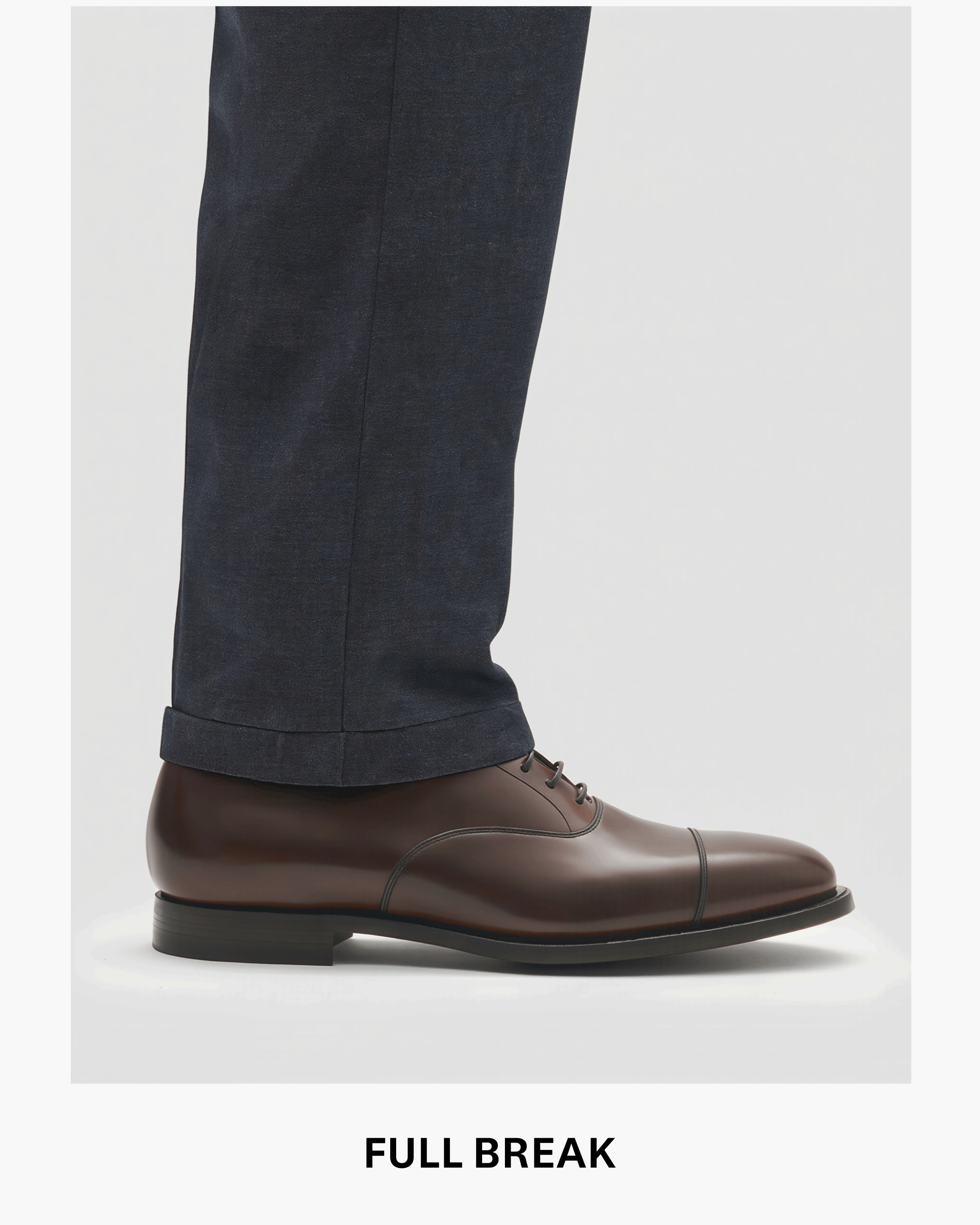 Dunkelblaue Herrenhose mit Full-Break-Länge über braunem Lederschuh, Nahaufnahme vom unteren Hosenbein.