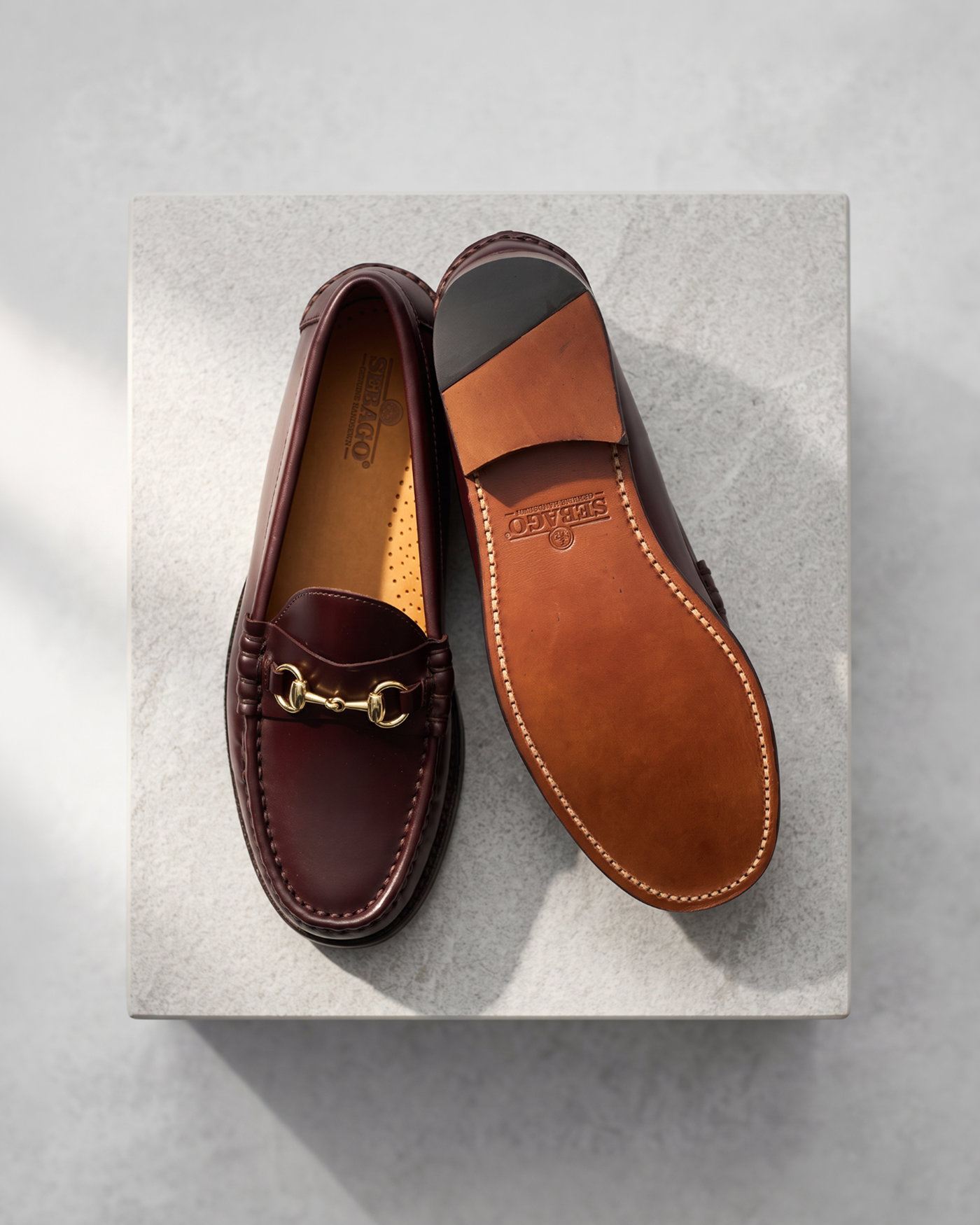 Braune Herren-Lederloafer mit goldener Trense, eine Schuhoberseite und eine Ledersohle mit Markenprägung.