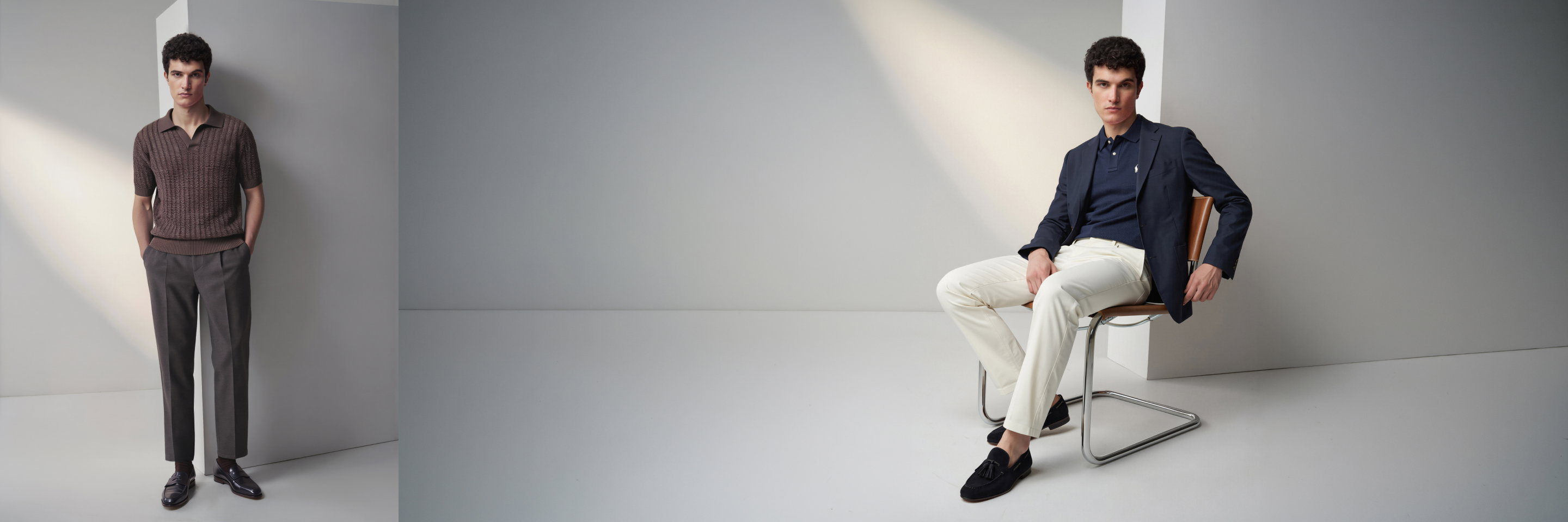 Zwei Männer in stilvollen Outfits: einer steht in braunem Strickshirt und grauer Hose, der andere sitzt in dunkelblauem Blazer und weißer Hose.
